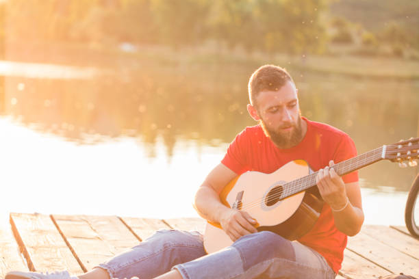 istock Hipster playing the guitar by the lake 814398002