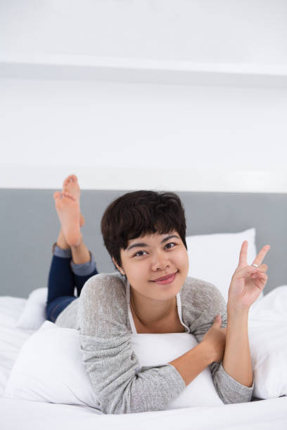 istock Content Girl Resting in Bed Showing Victory Sign 814398448