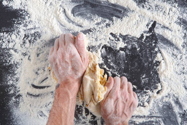 istock Hands top view knead dough on black background 814409678