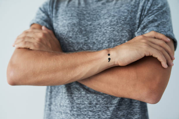Suicide awareness Studio shot of an unrecognizable man with a semi colon tattoo standing with his arms folded arm tattoo ideas for men pictures stock pictures, royalty-free photos & images