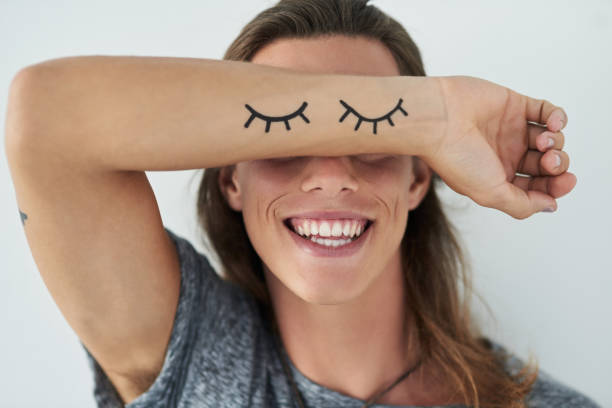 Smiling to match those eyes Cropped shot of a unrecognizable young man raising his arm in front of his eyes wrist tattoo stock pictures, royalty-free photos & images