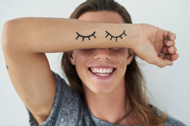 Smiling to match those eyes Cropped shot of a unrecognizable young man raising his arm in front of his eyes tattoo arm stock pictures, royalty-free photos & images