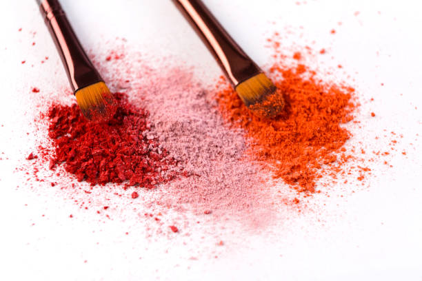 istock Makeup brushes with blush or eyeshadow of pink, red and coral tones sprinkled on white background 814454680