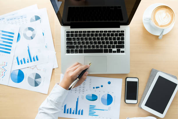 istock Business man working at office with laptop, tablet and graph data documents on his desk, top view 814484156
