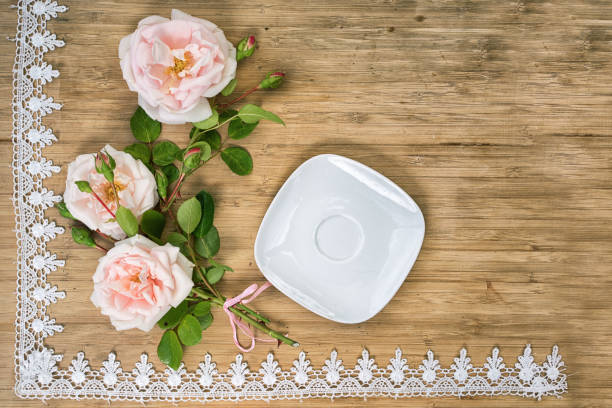 istock flat lay of pink roses with empty white sauser on a wooden table with lace frame and copy space for your text 814490304