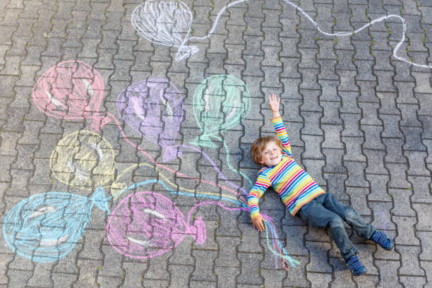istock Kid boy having fun with colorful balloons drawing with chalks 814515758