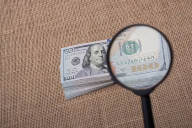 istock Magnifying glass over the banknote bundle of US dollar 814520882