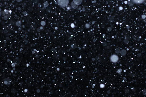 Texture tempesta di neve. Luci Bokeh e neve cadenti su sfondo nero - foto stock