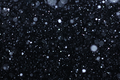 Snowstorm texture. Bokeh lights and Falling snow on a black background