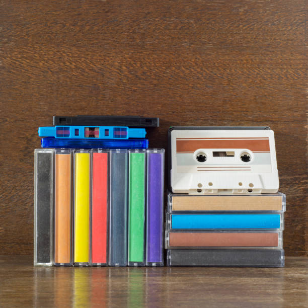 Stack of old colorful audio cassettes and cases on the brown wooden shelf
