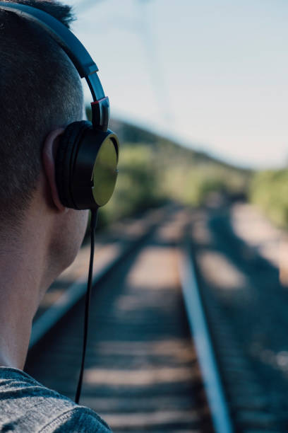 young man with headphones at the railroad tracks - railroad junction audio imagens e fotografias de stock