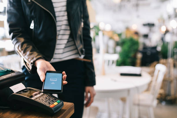Woman Paying With Smartphone. Woman using smartphone to pay in a store. Close up. digital wallet photos stock pictures, royalty-free photos & images