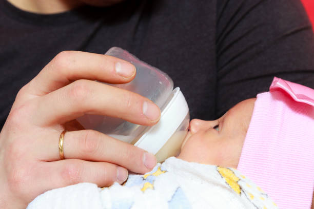 istock Little newborn baby lying, drinking from bottle 814580042