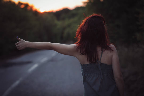 istock Woman hitchhiking on highway at sunset 814593720