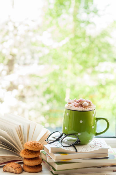 istock Coffee cup, open book, glasses, cookies on window with bokeh. Reading and breakfast. Concept warm and cozy home 814605022