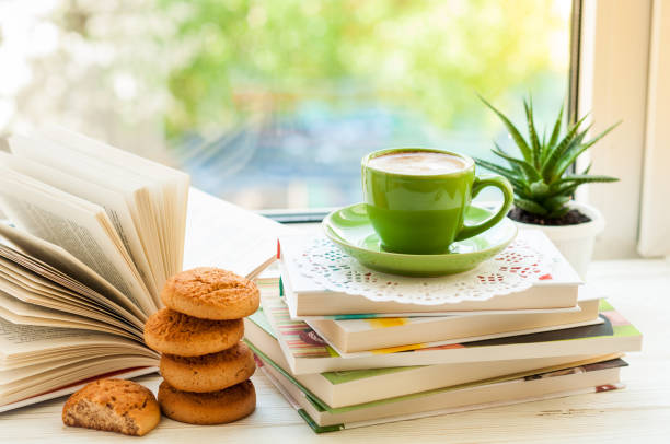 istock Coffee cup, open book, cookies and flower on window with bokeh. Reading and breakfast. Concept cozy home 814605032