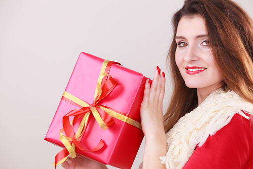 Cheerful woman holding present big red gift box. Christmas season celebration concept.