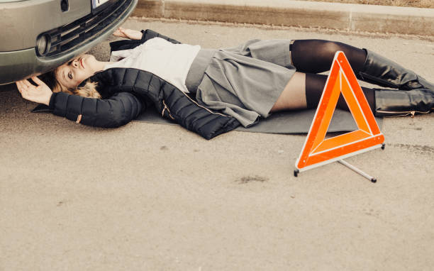 istock Woman, repairing broken car lying under it 814629722