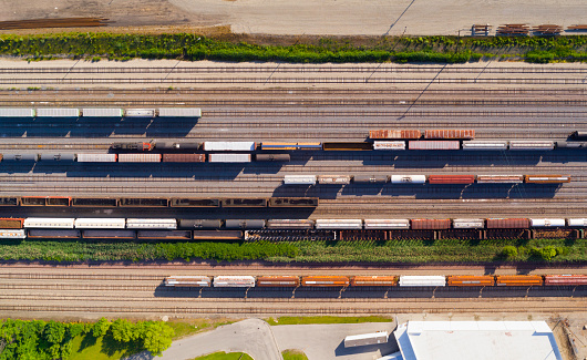 Looking straight down on industrial railroad rail train yard, many trains, tracks. Dynamic aerial view.