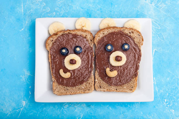 istock Funny bear face sandwiches with chocolate paste, banana, nuts, and berries. Kids breakfast with sandwiches and milk 814669162