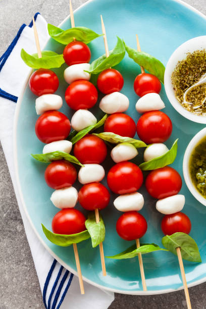 istock Appetizing vegetarian kebabs from cherry tomatoes and mini mozzarella in two kinds of basil and oregano sauce as a snack 814758642