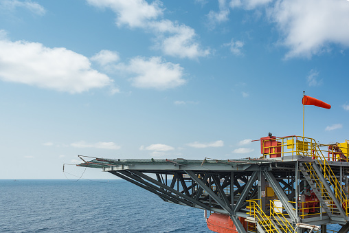 Side view of jack up oil and gas rig helipad in the Gulf of Thailand with blue sky
