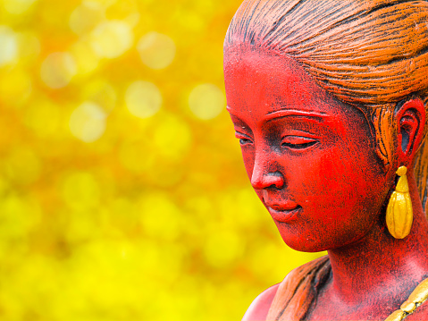Close up of The Statue of asian woman on golden bokeh background with Clipping path.