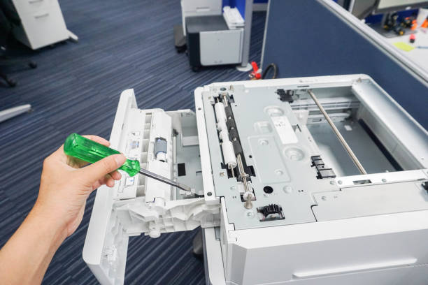 engineer left hand use green screwdriver repair office printer tray and other parts stock photo