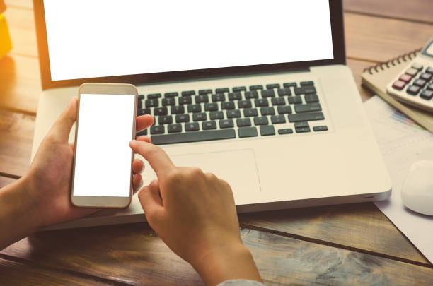 istock Hand holding smartphone for working on laptop 814912036