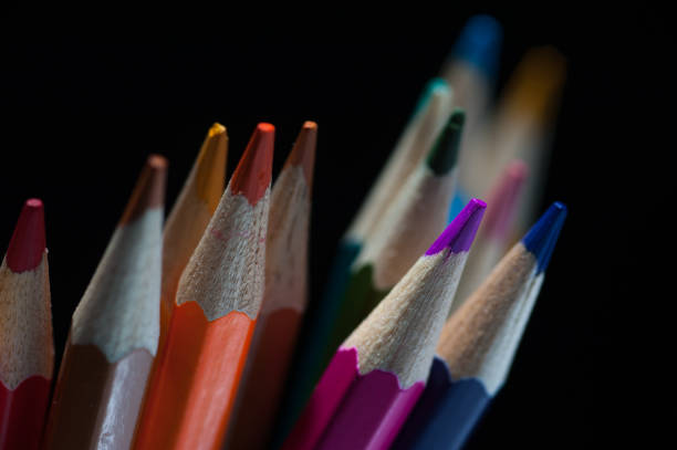 Group of colorful sharpened pencils on black background. Assortment of stationary supplies. Drawing and sketching tools.
