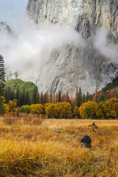 A photographer/hiker is taking pictures of El Capitan at El Capitan Meadow at Yosemite National Park