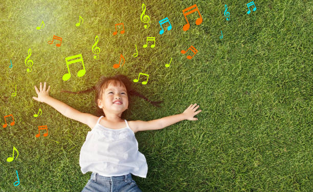 little girl smile Asian little girl smile and lay on grass with music note background musical note photos stock pictures, royalty-free photos & images