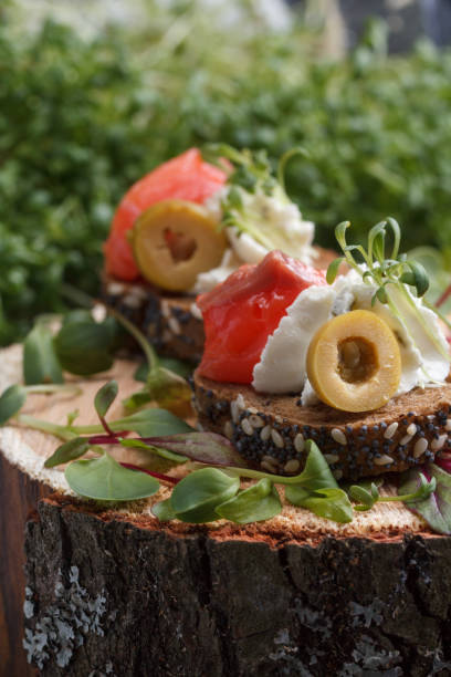 istock Delicious canape with salmon, cottage cheese, olive with micro greens on a dark background. Cold appetizer. 814945220