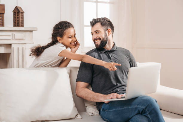 istock cheerful girl pointing at laptop screen while father sitting on sofa 814959816