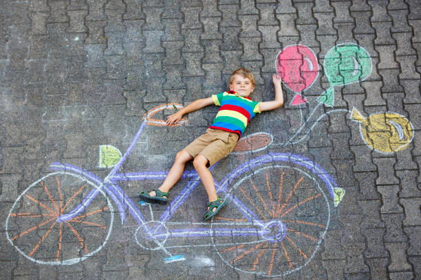 istock little kid boy having fun with bicycle chalks picture on ground 814985788