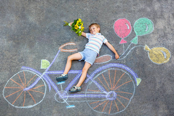 istock little kid boy having fun with bicycle chalks picture on ground 814985942