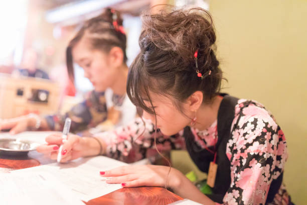 istock Young women in matsuri outfit writing document in restaurant 814988600