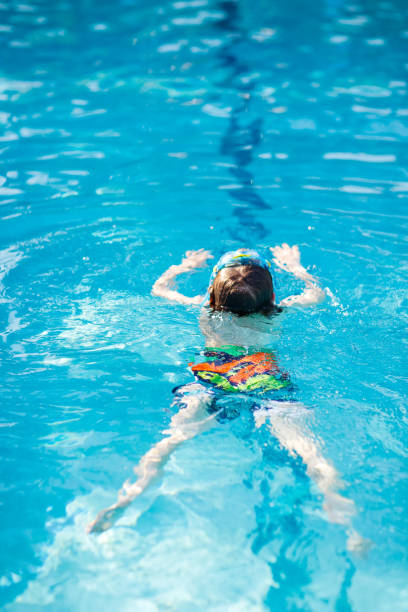 istock Little kid boy making swimming competition in pool 814989574