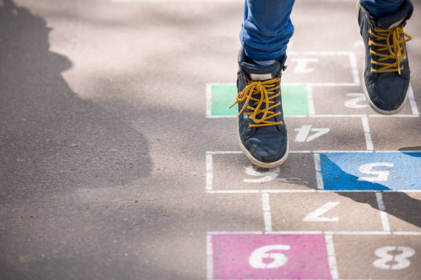 Closeup of boy's legs and hopscotch drawn on asphalt. Child playing hopscotch on playground outdoors on a sunny day. outdoor activities for children. Closeup of boy's legs and hopscotch drawn on asphalt. Child playing hopscotch on playground outdoors on a sunny day. outdoor activities for children. schoolyard photos stock pictures, royalty-free photos & images