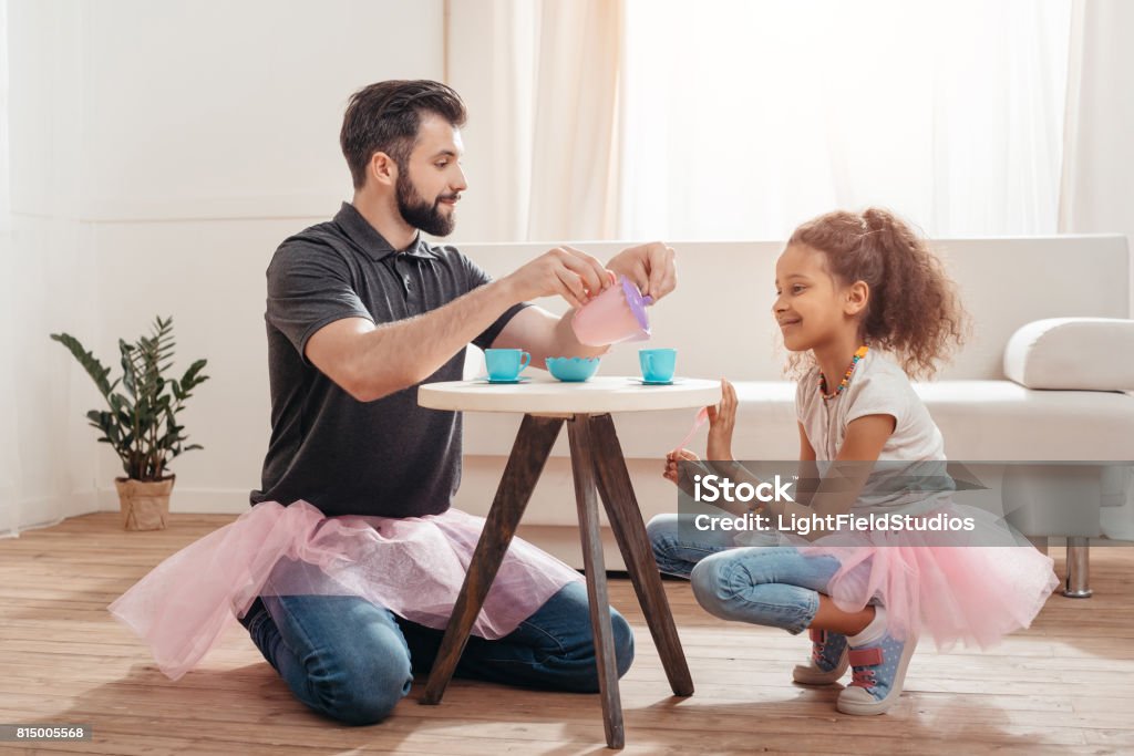 multicultural father and little daughter having tea party at home Tea Party Stock Photo