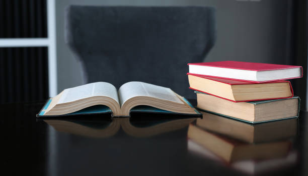 istock Open book and stack of hardcover books on wooden table. 815005836