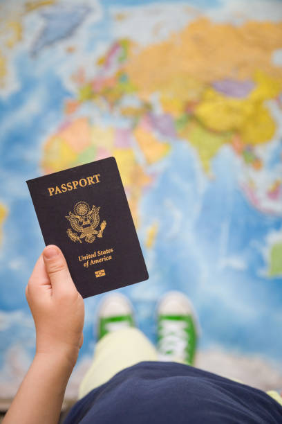 Child's hand holding US passport. Map background. Ready for traveling. Open world.