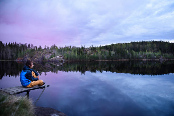 istock Man sitting on a pier at mountain lake, looking at view. 815039230