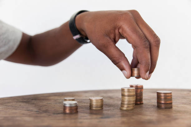 Man stacking coins. Close up of an african male hand stacking up coins. counting coins stock pictures, royalty-free photos & images