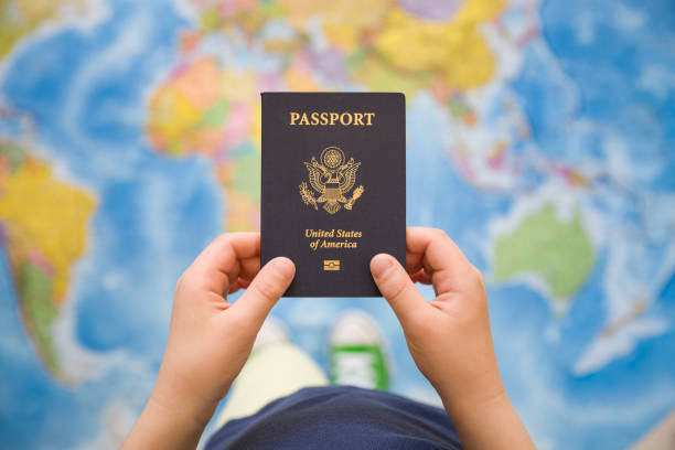 istock Child's hand holding US passport. Map background. Ready for traveling. Open world. 815048326