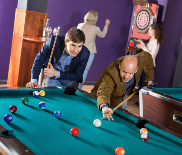 istock Group of happy charming positive friends playing billiards 815050468