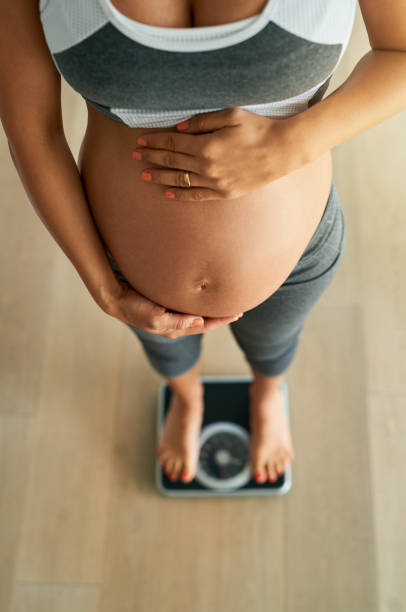управление здоровой беременности увеличение веса с ежедневным весом ins - human pregnancy rubbing looking down abdomen стоковые фото и изображения