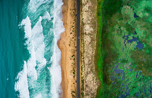 Aerial view of sea waves and beach, country road.
