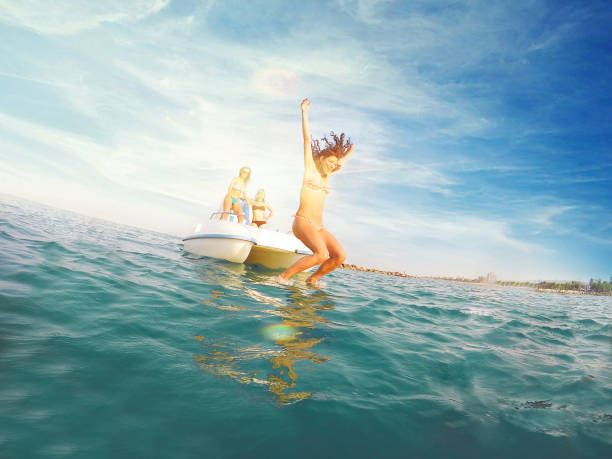 Three young women on pedal boat - Diving into water
