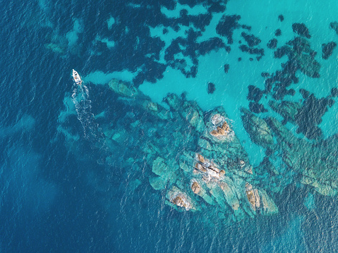 Aerial view of blue sea, rocks and a boat